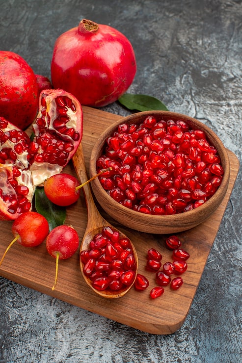 side-close-up-view-fruits-cutting-board-with-pomegranate-seeds-spoon-cherries-pomegranate_140725-74032